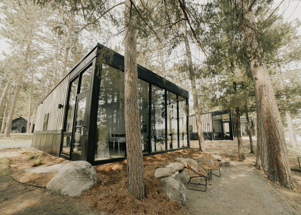 Modern cabin surrounded by pine trees at Nature Link Resorts, co-founded by the WOODCHUCK USA team.